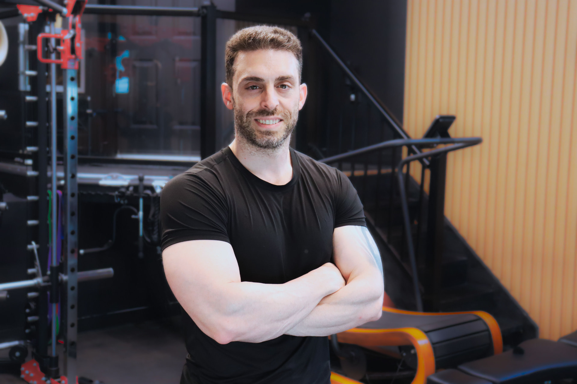 Adam standing with arms crossed in his gym