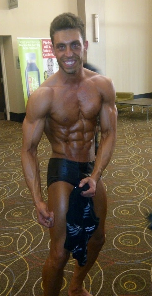 Adam on stage at a bodybuilding competition showing his rebuilt physique