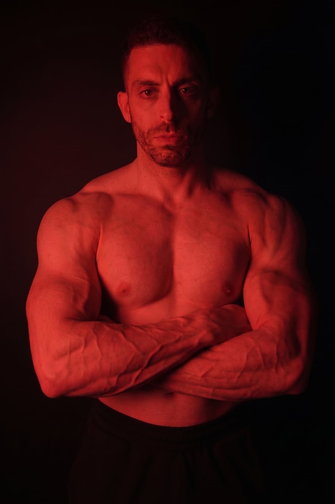 Adam standing with arms folded, facing the camera