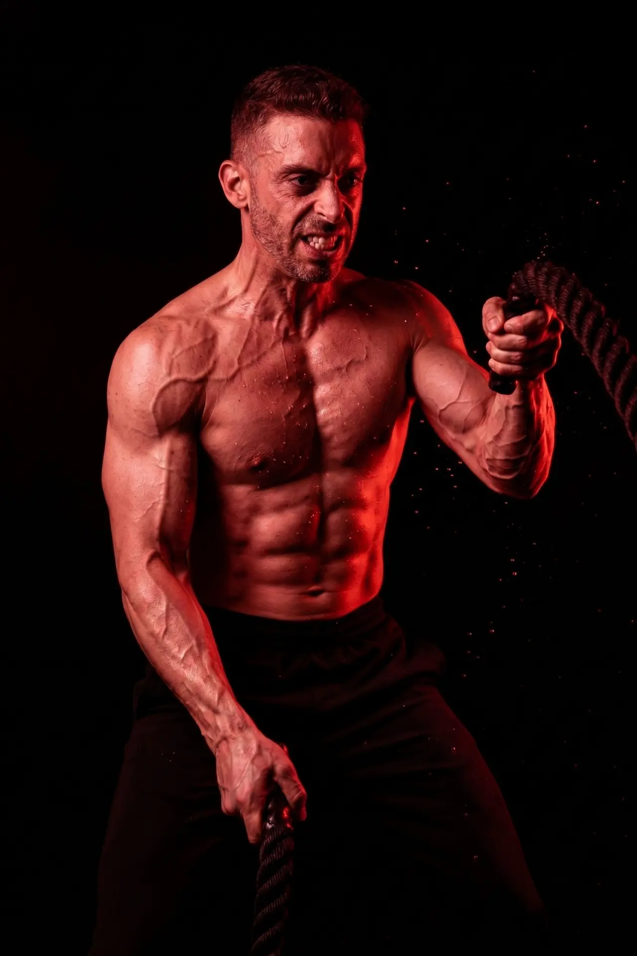 Adam training with battle ropes under red light