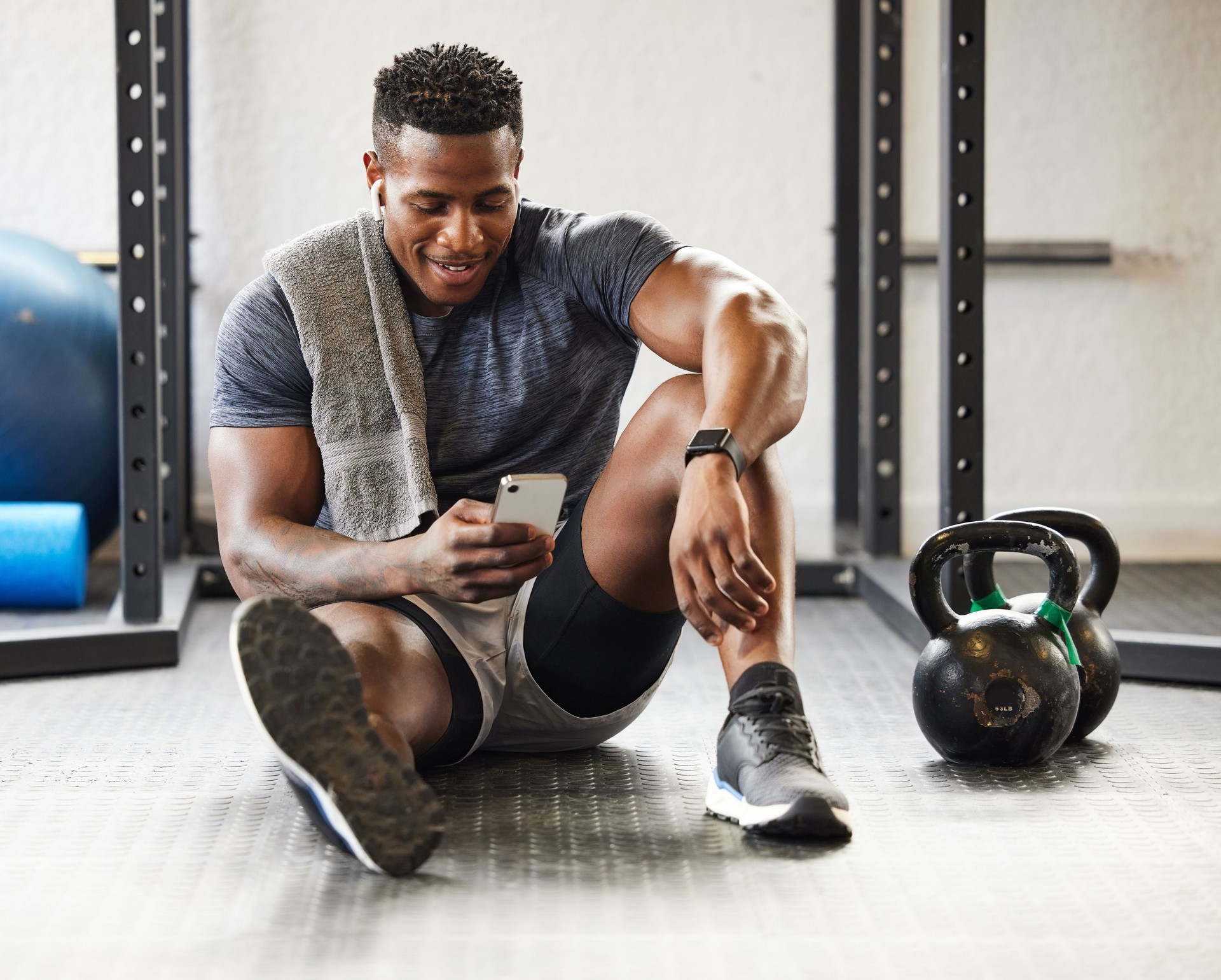 Shot of a muscular young man using a cellphone while exercising in a gym